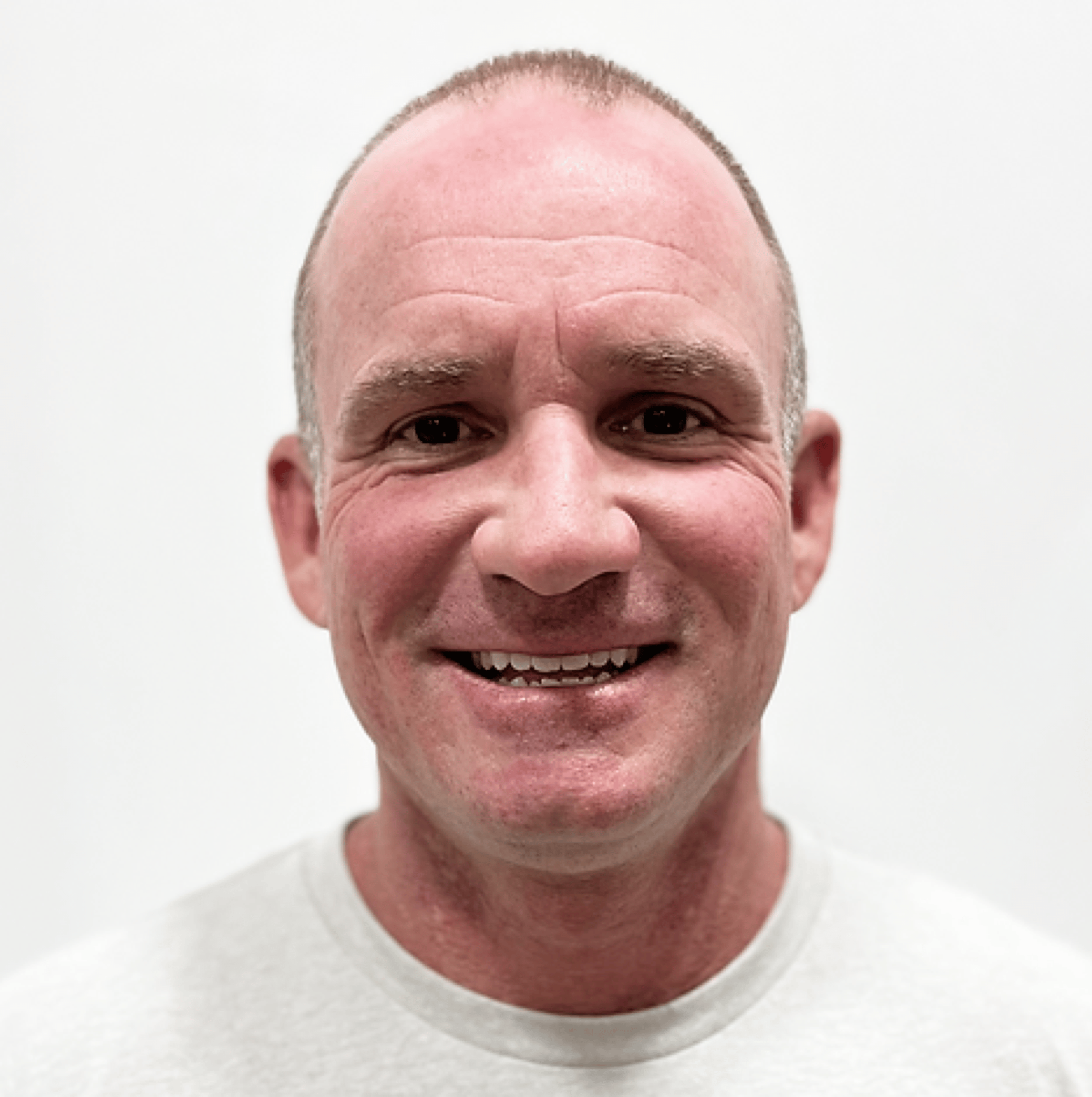 Smiling man with short hair wearing a light gray shirt against a plain background.